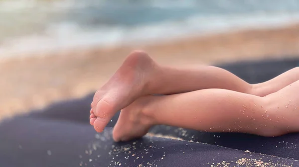 Su un materasso gonfiabile blu sulla spiaggia, le gambe dei bambini sullo sfondo dell'acqua di mare. — Foto Stock