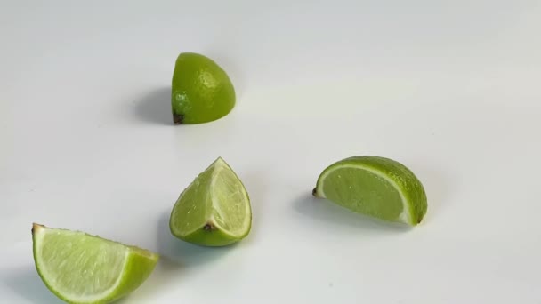 Les coins de chaux dansent de façon ludique sur la table, puis s'envolent et collent ensemble dans un citron vert entier. — Video