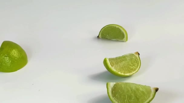 Лимонные клинья игриво танцуют на столе, а затем взлетают и держатся вместе в целую лайм. — стоковое видео