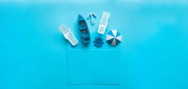Busta blu con lettino, ombrellone, barca, ancora, volante interno su fondo blu — Foto Stock