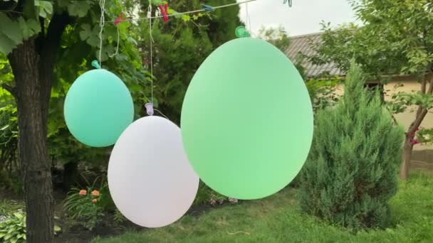 En el patio de una casa privada, globos cuelgan de una cuerda y se mueven en el viento. — Vídeos de Stock