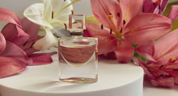 Beyaz arka planda çiçekli parfum. Pembe ve beyaz yapraklarla kaplı bir parfüm şişesi.