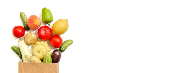 Una bolsa de compras de papel con verduras y frutas, tomate, pepino, calabaza, pimienta, limón, berenjena, calabacín, plátano, manzana, melocotón sobre fondo blanco — Foto de Stock