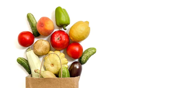 Una bolsa de compras de papel con verduras y frutas, tomate, pepino, calabaza, pimienta, limón, berenjena, calabacín, plátano, manzana, melocotón sobre fondo blanco — Foto de Stock