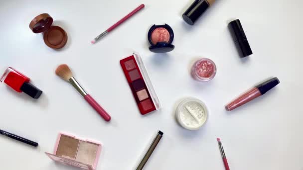 Concept beauté. Vidéo stop motion où les produits de maquillage ombres, surligneur, blush, pinceaux, poudre, paillettes, mascara, brillant, rouge à lèvres, crayon dansant sur fond blanc. — Video