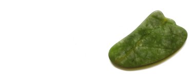 Beyaz arka planda yüz ve vücut masajı için Guasha kazıyıcısı var. Güzellik ve kişisel bakım konsepti