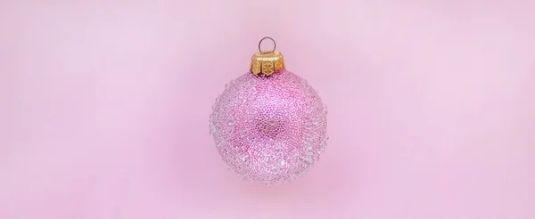 Palla di Natale rosa con alcuni dossi su uno sfondo rosa. Design natalizio minimale, posto per testo — Foto Stock