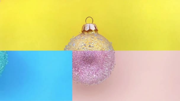 Boules de Noël jaune, vert, bleu, rose dans l'animation stop motion alterne avec des couleurs en choisissant une paire de deux moitiés. — Video