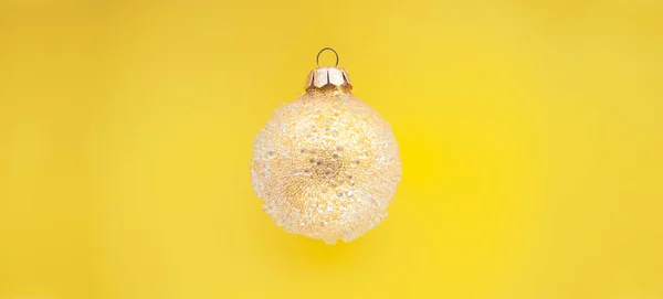Gelbe Weihnachtskugel mit einigen Unebenheiten auf grünem Hintergrund. Minimales Weihnachtsdesign, Platz für Text — Stockfoto