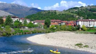 İspanya 'nın Asturias kentindeki Arriondas kasabasının içinden sakin bir nehrin aktığı pitoresk bir videosu. Kamera, geleneksel mimari astarlı bir dizi büyüleyici binayı yakalar.