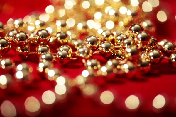 Χρυσές χάντρες σε κόκκινο με θολή φώτα bokeh — Φωτογραφία Αρχείου