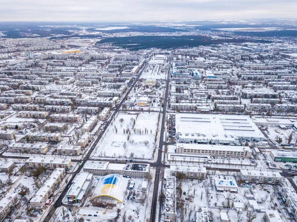 Top view from drone of city roads and houses covered with snow.