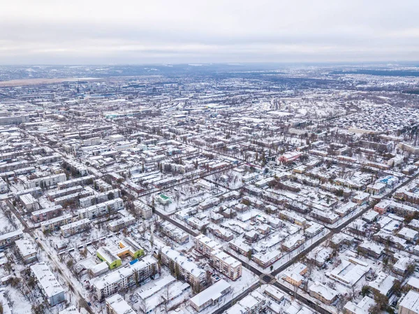 Top view from drone of city roads and houses covered with snow.