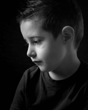 Üzgün görünen bir çocuğun siyah beyaz fotoğrafı.