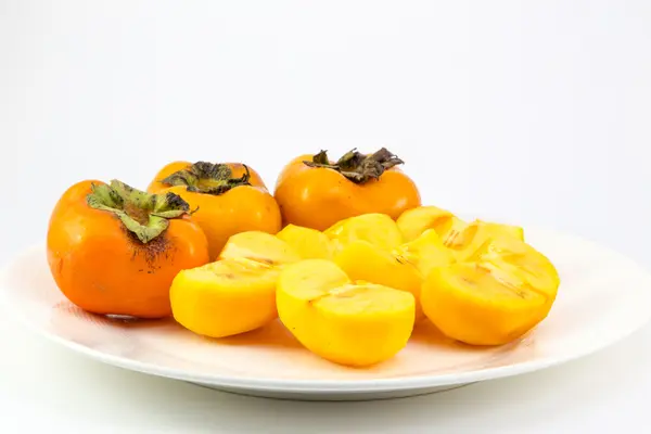 Persimmon fruit on white dish — Stock Photo, Image