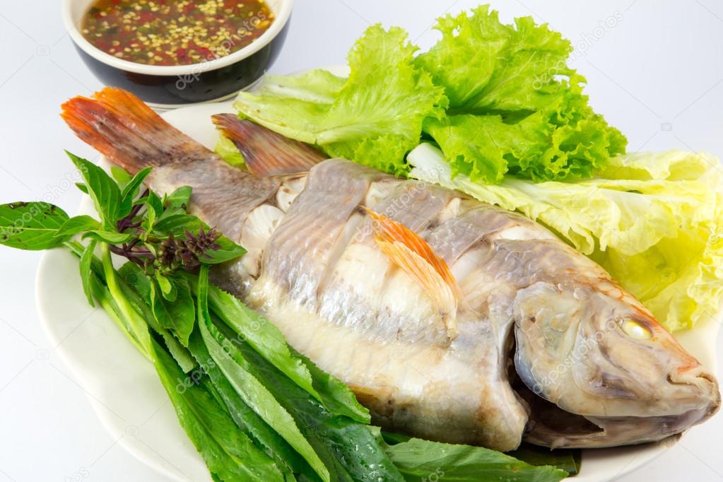 Steamed Fish with vegetables and sauce on white background