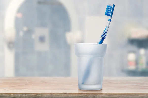 Cepillo de dientes en vidrio en estante — Foto de Stock