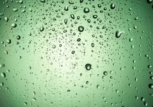 Краплі на склі з зеленим сяйвом — стокове фото
