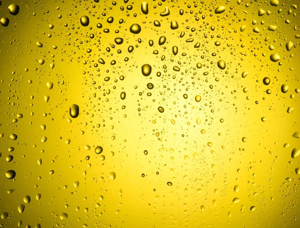 Druppels op glas met gele gloed — Stockfoto