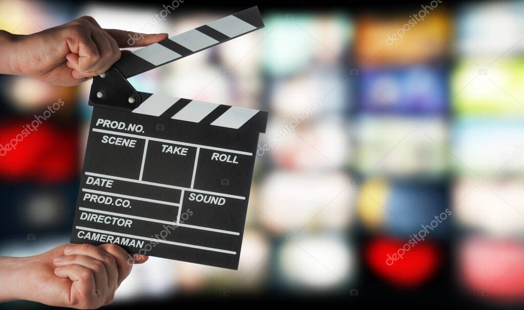 Clapperboard in hands on the background of TV screens