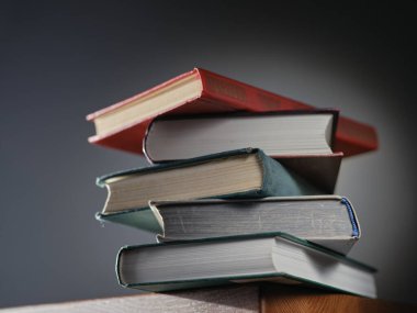 Masanın arkasında bir sürü kitap var.