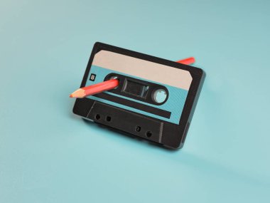 Mavi arkaplanda klasik ses kaseti ve kalem