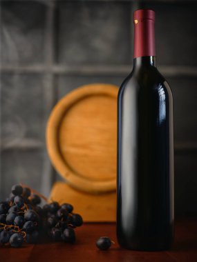 Masanın üzerinde bir demet üzüm olan bir şişe şarap.