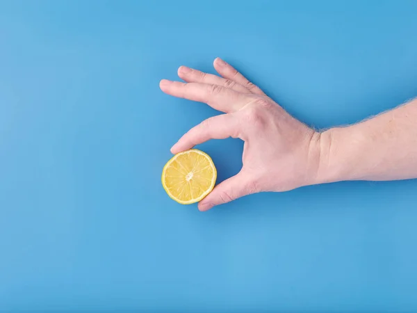 Lemon in hand on blue background