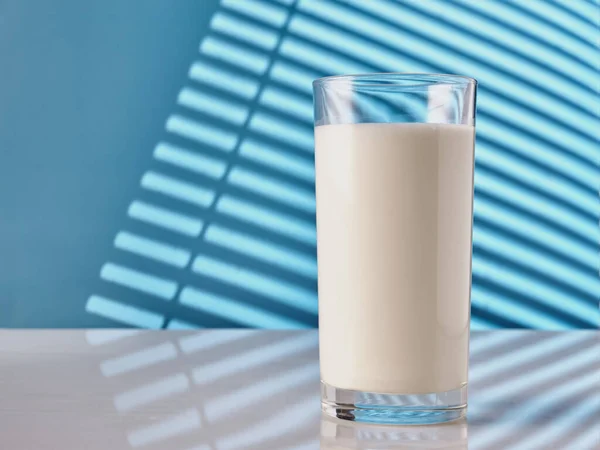 Bicchiere Latte Tavolo Bianco Con Parete Blu Alla Luce Del — Foto Stock