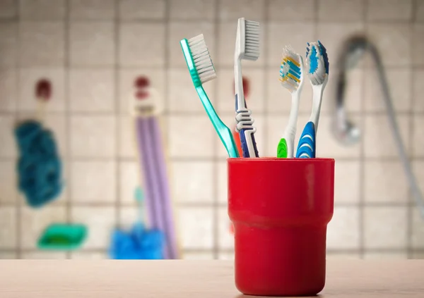 Toothbrushes in red glass — Stock Photo, Image