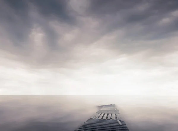 Pier in a fog on coastline — Stock Photo, Image