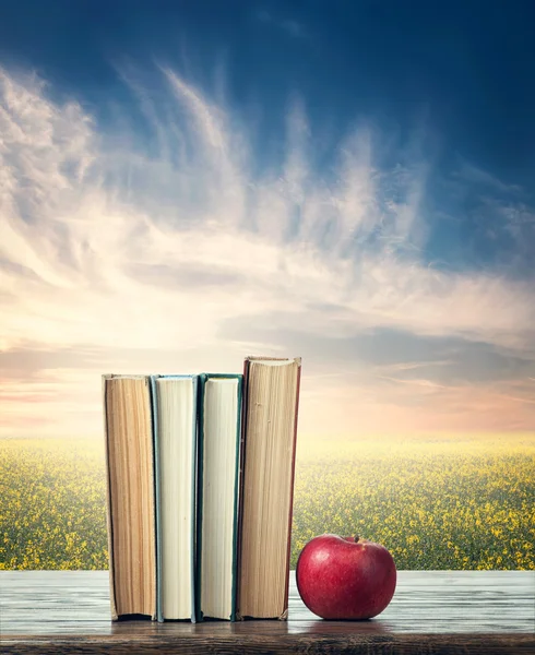 Boeken en apple op natuurlijke achtergrond — Stockfoto