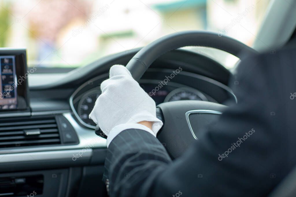 View on the dashboard of the car driving.The driver is holding the steering wheel. Forest road is in front of the car.Limousine driver driving and smiling in his limousine.