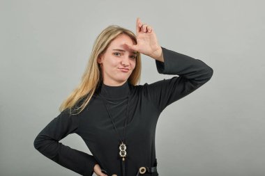 Ezik işareti gösteriliyor, işe yaramaz bir jest sergiliyor. İki parmak 2, yüzünde iğrenme.