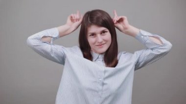 Komik bir portre. Duygusal bir yüz. Neşeli genç şov boynuzları Elleri başının üstünde.