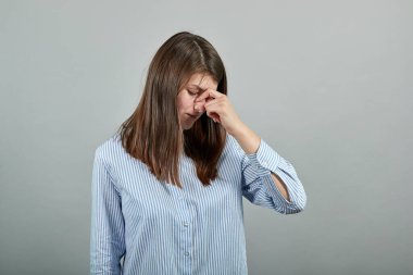 Burnunu eliyle kapatarak pis kokan, izole edilmiş, elleri ters dönmüş bir şey gösteriyor.