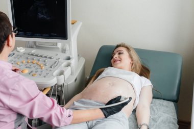 Hamile bir kıza klinikte ultrasondan sonra doktor tarafından tavsiye edilir. Tıbbi muayene