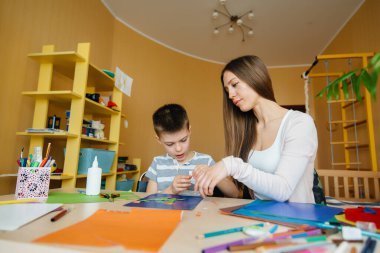 Genç bir anne evde oğluyla ev ödevi yapıyor. Ebeveynler ve eğitim