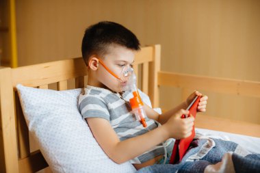 Bir çocuk akciğer solunumu sırasında tabletle oynuyor. İlaç ve bakım