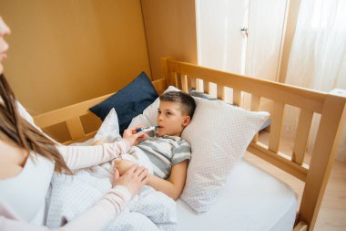 Ateşi ve ateşi olan bir anne çocuğuna bakar. Hastalık ve sağlık hizmetleri