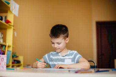 Okul çağındaki bir çocuk evde ödev yapar. Okulda eğitim.