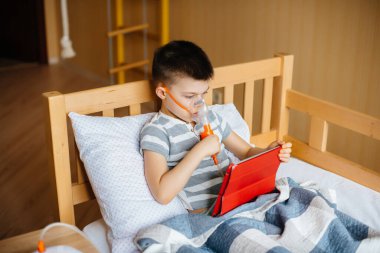 Bir çocuk akciğer solunumu sırasında tabletle oynuyor. İlaç ve bakım