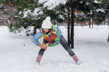Genç bir atletik kız soğuk bir günde koşmadan önce ısınıyor. Fitness, çalışma