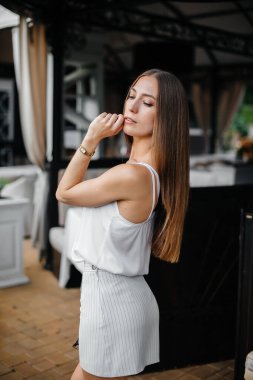 Güzel bir genç kız güzel bir evin verandasında duruyor..