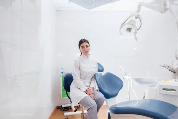 A professional dentist stands in a modern light dental office. Dentistry