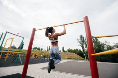 Seksi kız açık havada yatay bir çubuğa çekiliyor. Fitness. Sağlıklı yaşam tarzı