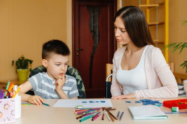 Genç bir anne evde oğluyla ev ödevi yapıyor. Ebeveynler ve eğitim