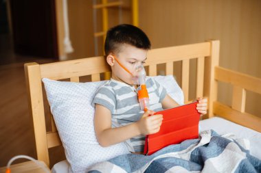 Bir çocuk akciğer solunumu sırasında tabletle oynuyor. İlaç ve bakım