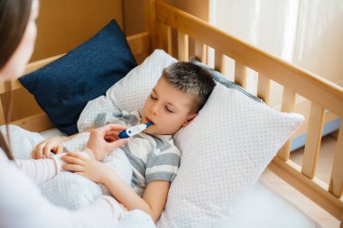 Ateşi ve ateşi olan bir anne çocuğuna bakar. Hastalık ve sağlık hizmetleri