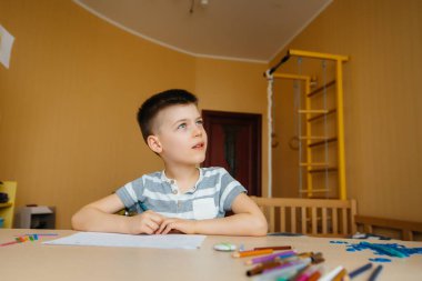 Okul çağındaki bir çocuk evde ödev yapar. Okulda eğitim.